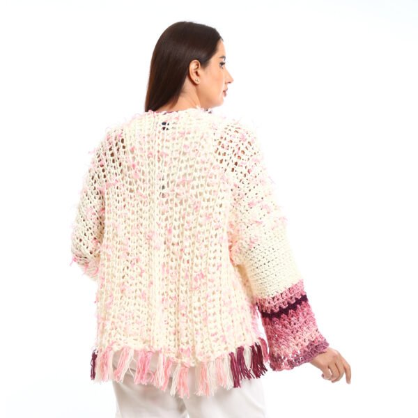 Handmade-looking crocheted open cardigan.is primarily cream-colored with pink featuring wide sleeves with color-blocked bands near the cuffs.