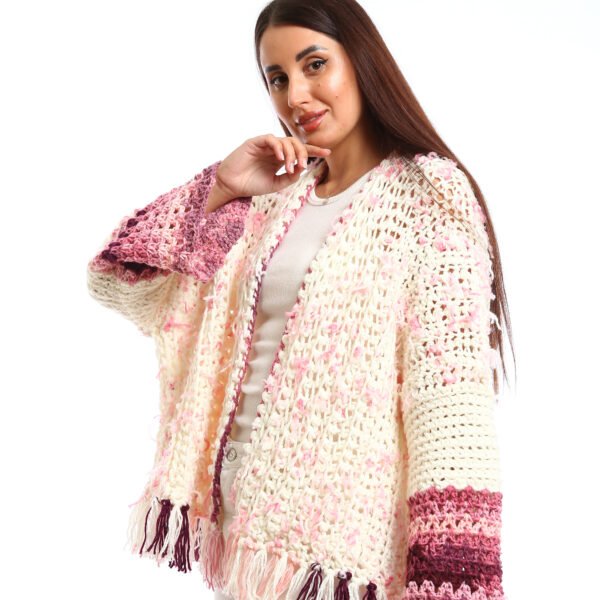 Handmade-looking crocheted open cardigan.is primarily cream-colored with pink featuring wide sleeves with color-blocked bands near the cuffs.