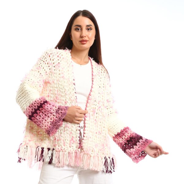 Handmade-looking crocheted open cardigan.is primarily cream-colored with pink featuring wide sleeves with color-blocked bands near the cuffs.